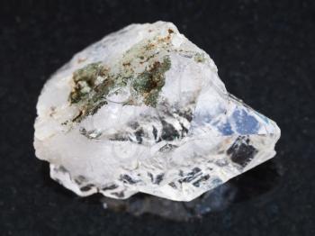 macro shooting of natural mineral rock specimen - rough rock crystal of quartz gemstone on dark granite background