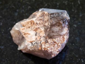 macro shooting of natural mineral rock specimen - raw crystal of smoky quartz gemstone on dark granite background