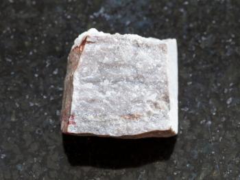 macro shooting of natural mineral rock specimen - rough Rhyolite stone on dark granite background
