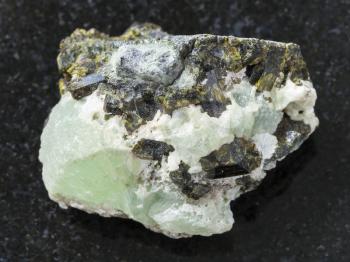macro shooting of natural mineral stone specimen - crystals of Epidote on prehnite gemstone on dark granite background