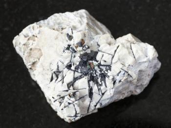 macro shooting of natural mineral rock specimen - Ilmenite black crystals on rough stone on dark granite background from Khibiny Mountains, Kola Peninsula in Russia