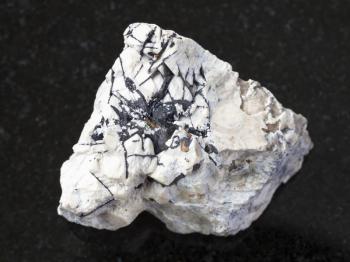 macro shooting of natural mineral rock specimen - Ilmenite black crystals on raw stone on dark granite background from Khibiny Mountains, Kola Peninsula in Russia