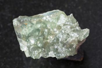 macro shooting of natural mineral rock specimen - green crystalline fluorite gemstone on dark granite background from Usugli region of Zabaykalsky Krai in Russia