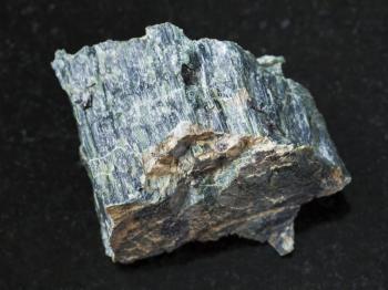 macro shooting of natural mineral rock specimen - raw chrysotile asbestos stone on dark granite background from Saranovskoe mine, Ural Mountains, Russia
