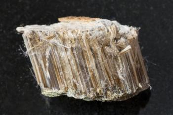 macro shooting of natural mineral rock specimen - raw brown asbestos stone on dark granite background from Bazhenovskoye mine in Ural Mountains, Russia