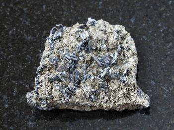 macro shooting of natural mineral rock specimen - magnetite crystals on raw stone on dark granite background from Korshunovskoe mine, Irkutsk region, Russia