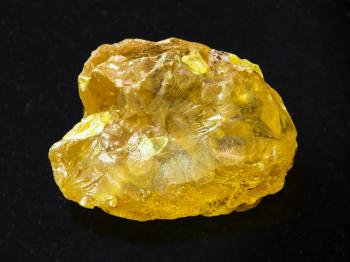 macro shooting of natural mineral rock specimen - raw crystal of sulphur stone on dark granite background from Samara region, Russia