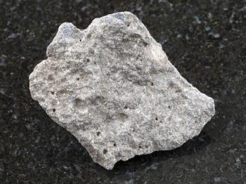 macro shooting of natural mineral rock specimen - pebble of gray basalt stone on dark granite background