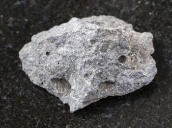 macro shooting of natural mineral rock specimen - piece of gray basalt stone on dark granite background