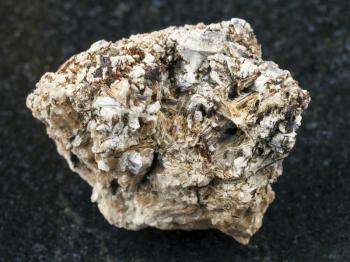 macro shooting of natural mineral rock specimen - brown Astrophyllite crystals in raw Natrolite stone on dark granite background from Khibiny Mountains, Kola Peninsula, Russia