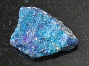 macro shooting of natural mineral rock specimen - rough blue Chalcopyrite stone on dark granite background from Mexico