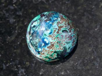 macro shooting of natural mineral rock specimen - cabochon from Chrysocolla gemstone on dark granite background