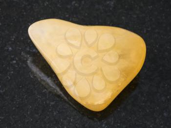 macro shooting of natural mineral rock specimen - tumbled yellow Aventurine gem stone on dark granite background from India