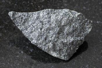 macro shooting of natural mineral rock specimen - raw dolerite (diabase) stone on dark granite background from Raikonkoski district, Karelia, Russia