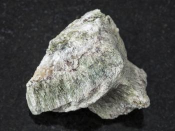 macro shooting of natural mineral rock specimen - rough richterite stone on dark granite background from Kovdor region, Kola Peninsula, Russia