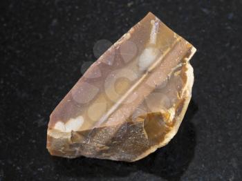 macro shooting of natural mineral rock specimen - rough brown Flint stone on dark granite background