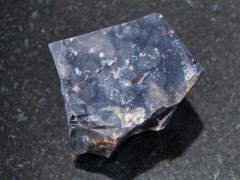macro shooting of natural mineral rock specimen - raw black Flint stone on dark granite background