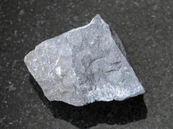 macro shooting of natural mineral rock specimen - raw argillite stone on dark granite background