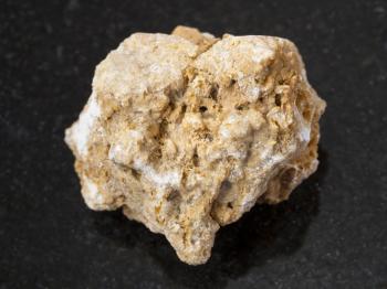 macro shooting of natural mineral rock specimen - rough travertine stone on dark granite background