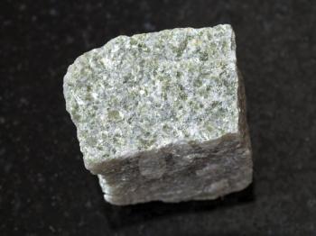 macro shooting of natural mineral rock specimen - rough quartz-mica schist stone on dark granite background
