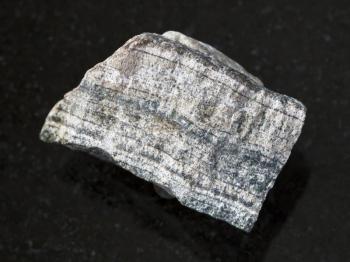 macro shooting of natural mineral rock specimen - piece of rough skarn stone on dark granite background