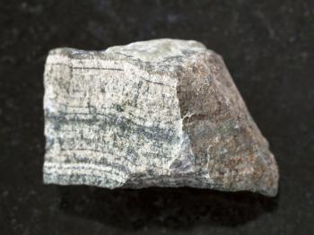 macro shooting of natural mineral rock specimen - piece of raw skarn stone on dark granite background