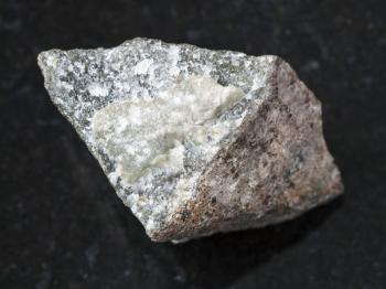 macro shooting of natural mineral rock specimen - piece of skarn stone on dark granite background