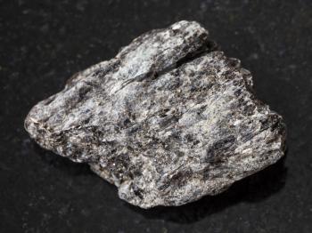 macro shooting of natural mineral rock specimen - raw quartz-biotite schist stone on dark granite background