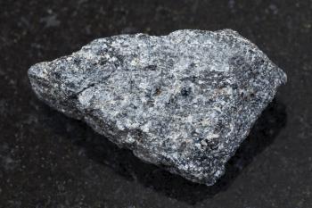 macro shooting of natural mineral rock specimen - raw nepheline syenite stone on dark granite background