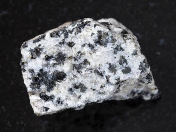 macro shooting of natural mineral rock specimen - rough white granite stone on dark granite background