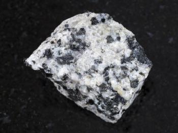 macro shooting of natural mineral rock specimen - raw white granite stone on dark granite background