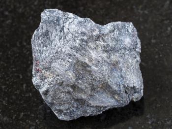 macro shooting of natural mineral rock specimen - rough antimony ore (Stibnite) stone on dark granite background from Ukraine