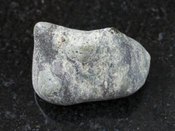 macro shooting of natural mineral rock specimen - pebble of Suevite stone on dark granite background from Karelia, Rissia