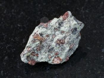 macro shooting of natural mineral rock specimen - rough eclogite stone on dark granite background from Salma region, Kola peninsula, Russia
