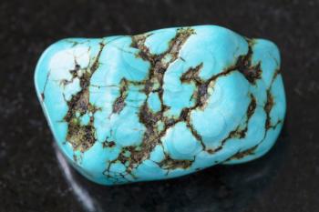 macro shooting of natural mineral rock specimen - polished blue howlite (turquenite) gem stone on dark granite background