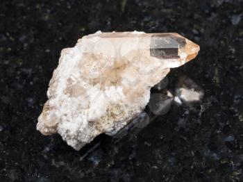 macro shooting of natural mineral rock specimen - rough crystal of topaz gemstone on dark granite background from Brazil