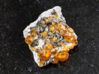 macro shooting of natural mineral rock specimen - crystals of spessartine gemstone on dark granite background from Fujian region, China