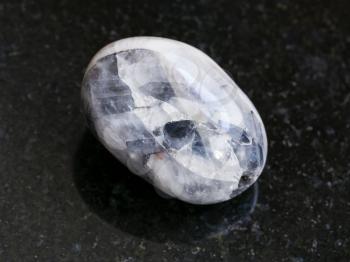 macro shooting of natural mineral rock specimen - polished Stone of Tamerlane (amethyst quartz) gemstone on dark granite background from Tajikistan
