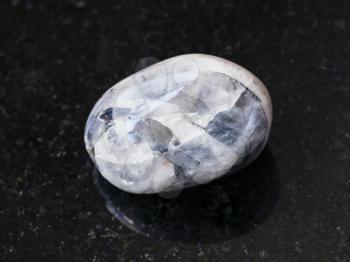 macro shooting of natural mineral rock specimen - tumbled Stone of Tamerlane (amethyst quartz) gemstone on dark granite background from Tajikistan