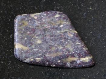 macro shooting of natural mineral rock specimen - polished Alunite stone on dark granite background from Zaglik, Dashkasan region of Azerbaijan