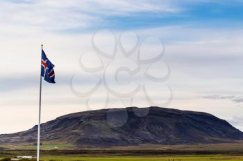 travel to Iceland - icelandic flag and view of hill near Kerid Lake in september evening