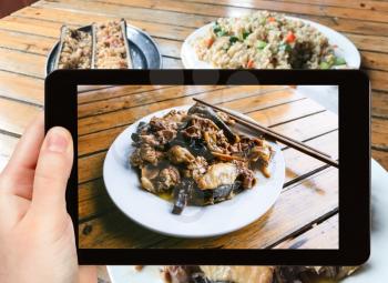travel concept - tourist photographs local chicken with mushrooms in rural eatery in area Dazhai Longsheng (Dragon's Backbone, Longji) Rice Terraces in China on tablet