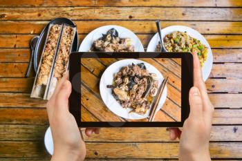 travel concept - tourist photographs local chinese food chicken with mushrooms in rural eatery in area Dazhai Longsheng (Dragon's Backbone, Longji) Rice Terraces in China on tablet