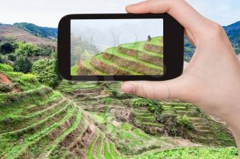 travel concept - tourist photographs terraced fields near Dazhai village in Longsheng (Dragon's Backbone, Longji) Rice Terraces county in China in spring on smartphone