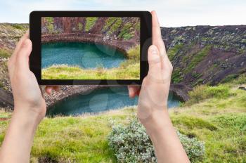 travel concept - tourist photographs old volcanic crater with Kerith lake in Iceland in september on tablet