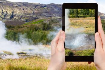 travel concept - tourist photographs Haukadalur geyser valley in Iceland in september on tablet