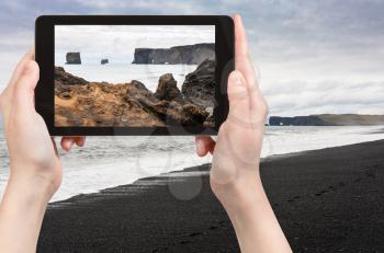 travel concept - tourist photographs Atlantic ocean volcanic coast and view of Dyrholaey promontory near Vik I Myrdal village on Atlantic South Coast in Katla Geopark in Iceland in september on tablet
