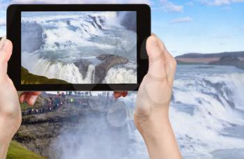travel concept - tourist photographs Gullfoss waterfall and people on observation deck in Iceland in september on tablet