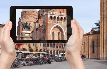 travel concept - tourist photographs monument of Gattamelata by Donatello and Basilica of Saint Anthony of Padua on square piazza del Santo in Padua city in Italy on tablet