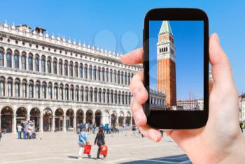 travel concept - tourist photographs campanile and Doge's palce on Piazza San Marco in Venice city in Italy in spring on smartphone